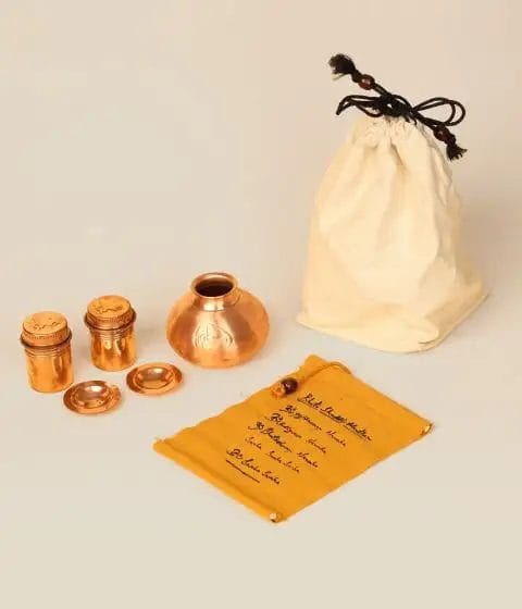 A set of copper utensils and a bag on a table.