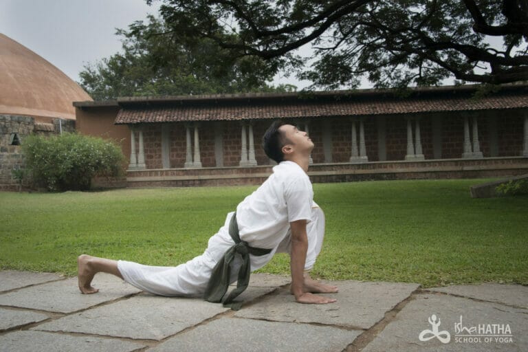 A man practicing Surya Kriya in front of a temple.