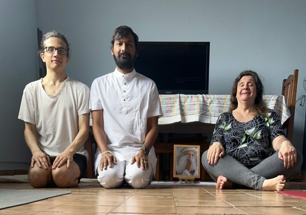 Three people sitting on the floor in front of a tv.