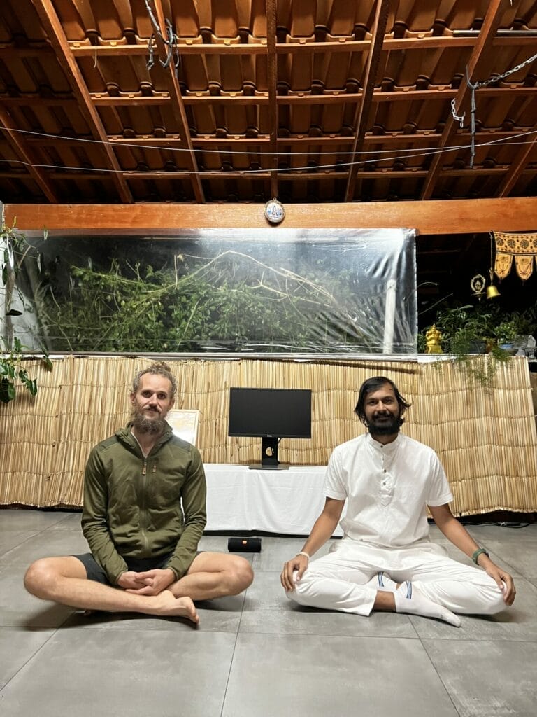 Two men meditating in front of a computer screen.