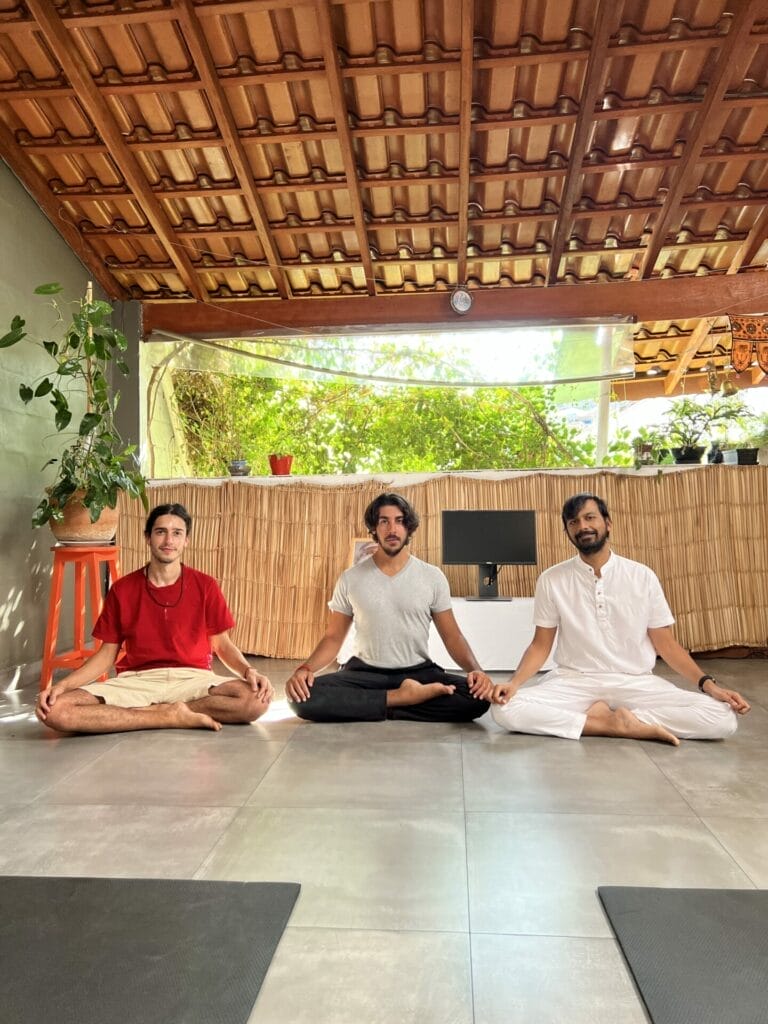 Three men sitting on the floor doing yoga.