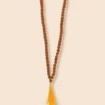 A rudraksha mala with brown beads and a yellow tassel.