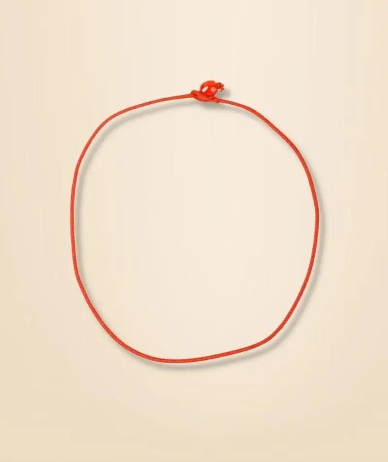 A simple red string tied in a knot forming a circle on a beige background.