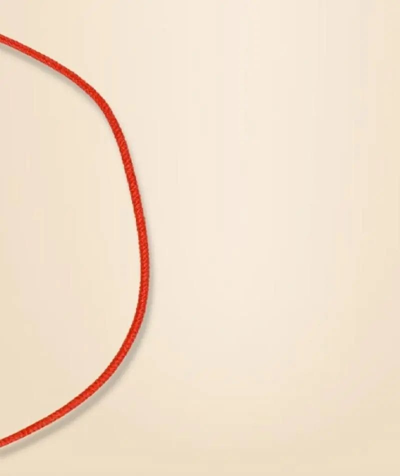 A red rope forms a loose loop on a beige background.