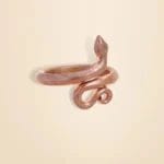 Bronze snake-shaped ring on a beige background.